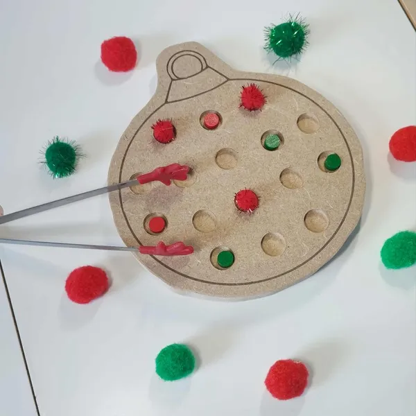 Activité Montessori avec plateau de motricité fine en bois en forme de boule de Noël et pompons rouges et verts manipulés à la pince