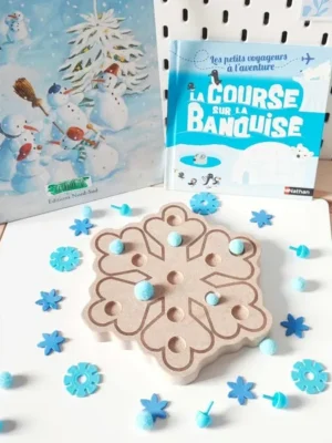 Plateau de motricité fine en bois en forme de flocon, décoré de pompons bleus et accompagné de livres sur le thème de l’hiver et de la banquise