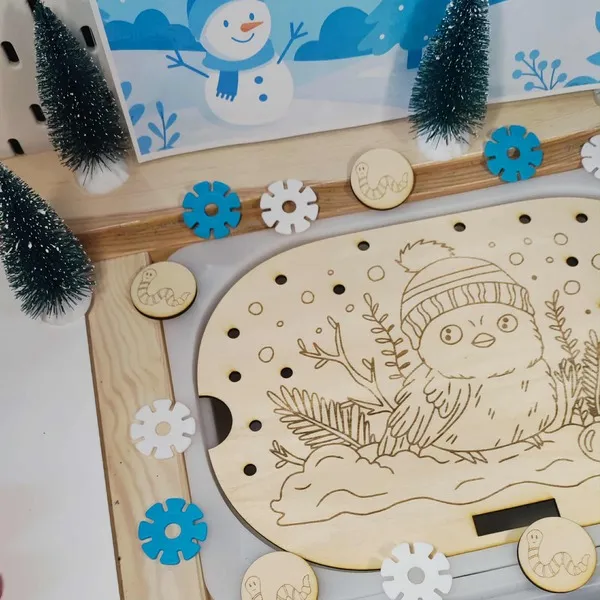 Plateau en bois gravé d’un oiseau d’hiver avec bonnet, entouré de jetons flocons et de petits sapins enneigés pour activité Montessori sur le thème de l’hiver