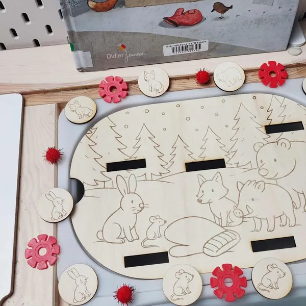 Plateau en bois thème La Moufle avec animaux gravés et jetons assortis positionnés autour du support d’activité