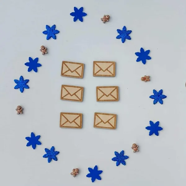 Six petites lettres en bois gravées entourées de flocons bleus et de mini bonshommes pain d’épices, accessoires du plateau sensoriel facteur du Père Noël