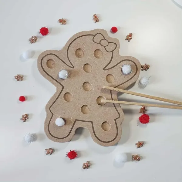 Plateau de motricité fine en bois en forme de bonhomme pain d’épices, décoré de pompons rouges et blancs avec baguettes de préhension
