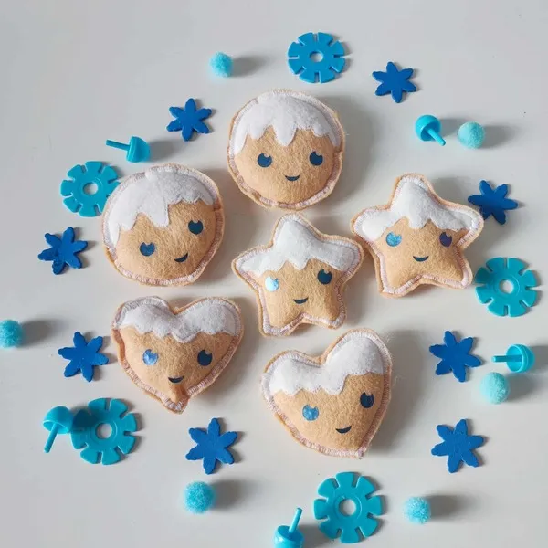 Petits biscuits enneigés en feutrine artisanale avec visages souriants, flocons et pompons bleus pour activité sensorielle Montessori hiver