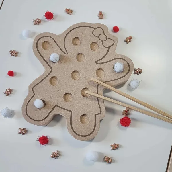 Plateau de motricité fine en bois MDF en forme de bonhomme pain d’épices, utilisé avec des baguettes et des pompons colorés sur fond blanc