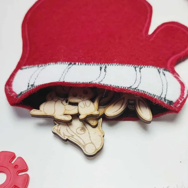 Animaux en bois glissés dans une moufle en feutrine rouge utilisée pour l’activité du conte La Moufle.