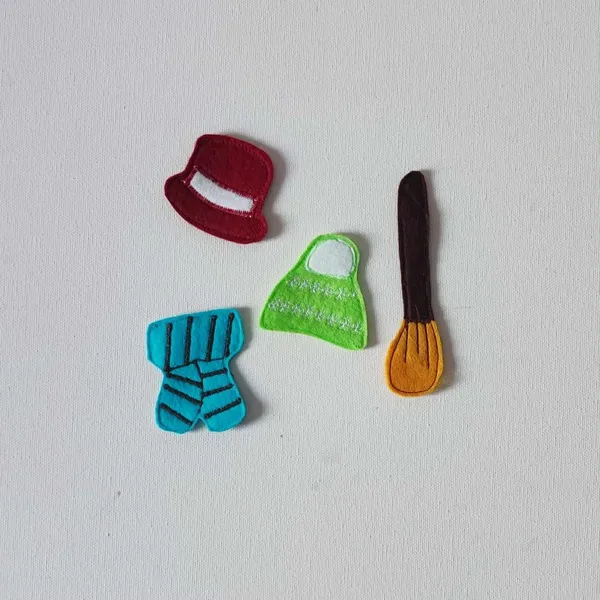 Accessoires d’hiver en feutrine colorée comprenant un chapeau rouge, un bonnet vert, une écharpe bleue et un balai, éléments de jeu pour activité créative sur le thème du bonhomme de neige