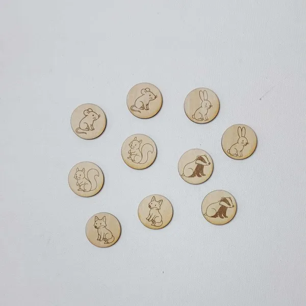Jetons en bois gravés représentant les animaux du conte La Moufle, disposés en cercle sur fond clair.