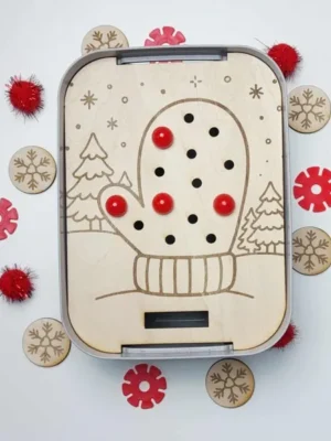 Plateau d’activité en bois gravé représentant une moufle d’hiver avec trous pour pompons, accompagné de jetons flocons en bois.