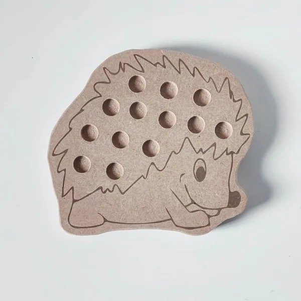Plateau de motricité fine en forme de hérisson en MDF, avec trous pour pompons, posé sur fond blanc.
