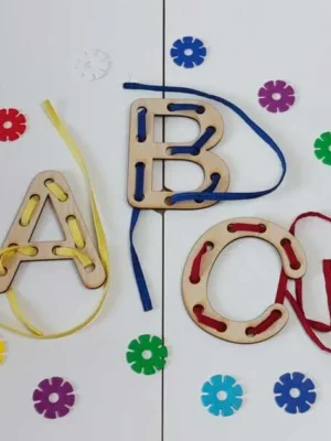 Lettres en bois A, B et C avec lacets colorés enfilés à travers les trous.