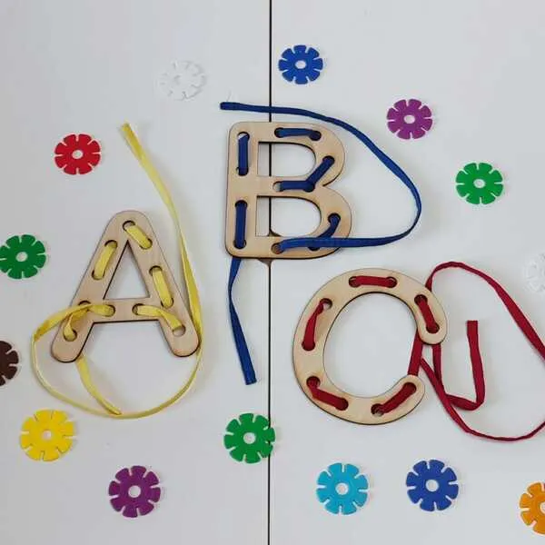 Lettres en bois A, B et C avec lacets colorés enfilés à travers les trous.