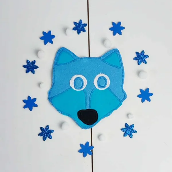 Tête de loup en feutrine bleue entourée de flocons bleus et de boules blanches, présentée sur fond clair