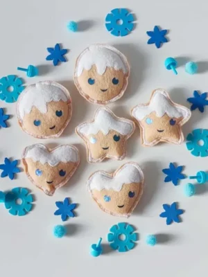 Biscuits d’hiver en feutrine artisanale avec visages souriants, flocons bleus et pompons pour activité sensorielle Montessori
