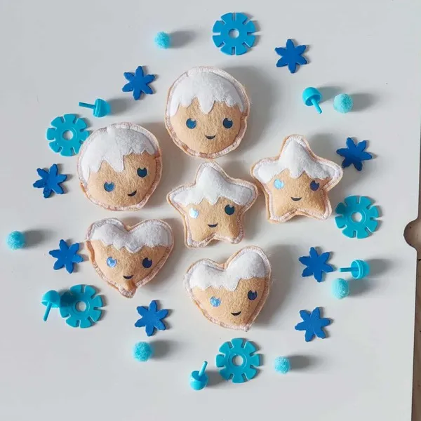Biscuits d’hiver en feutrine artisanale avec visages souriants, flocons bleus et pompons pour activité sensorielle Montessori
