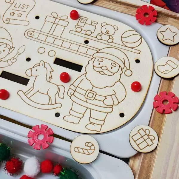Plateau d’activité en bois illustrant le Père Noël, entouré de jetons gravés et de pompons sensoriels colorés.