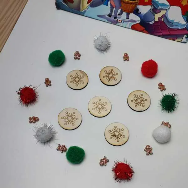 Jetons en bois gravés de flocons entourés de pompons festifs et de mini personnages pain d’épices.