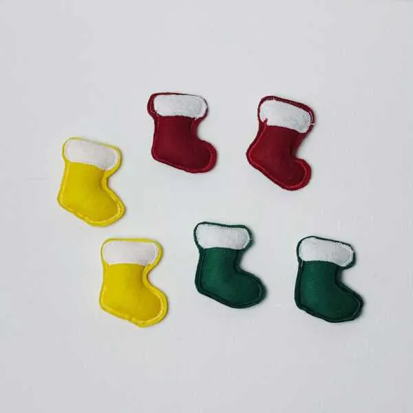 Six petites chaussettes de Noël en feutrine rouge, jaune et verte disposées en cercle sur un fond blanc.