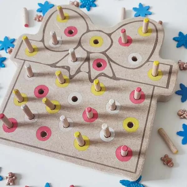 Détail du plateau de motricité fine cadeau de Noël en bois avec nœud et pics colorés à insérer