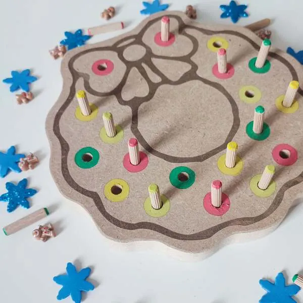 Gros plan sur le plateau de motricité fine couronne de Noël en bois avec pics colorés à insérer