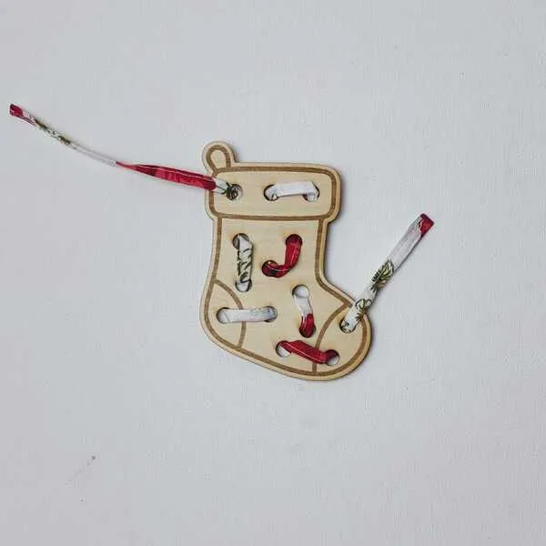Carte à lacer en bois en forme de chaussette de Noël avec un ruban décoratif passé dans plusieurs ouvertures.