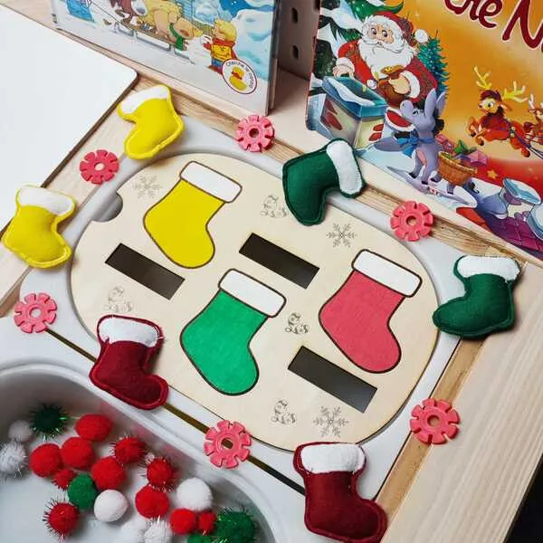 Plateau en bois de tri des bottes de Noël avec bottes en feutrine jaunes, vertes, rouges et pompons festifs présentés dans un bac sensoriel.