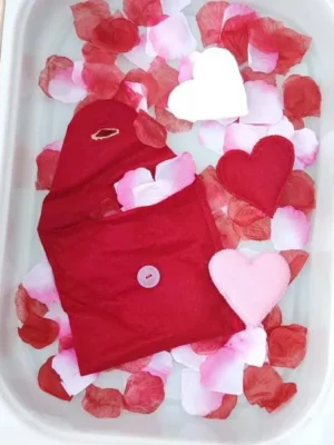 Pochettes en feutrine en forme de cœur avec cœurs assortis dans un bac sensoriel sur le thème de la Saint-Valentin