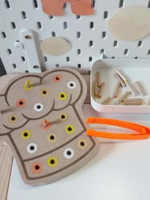Plateau pic en bois en forme de tablier avec chevilles colorées et pince, activité de motricité fine enfant