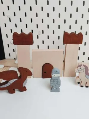 Figurines en bois représentant un chevalier, un dragon et un cheval devant un château