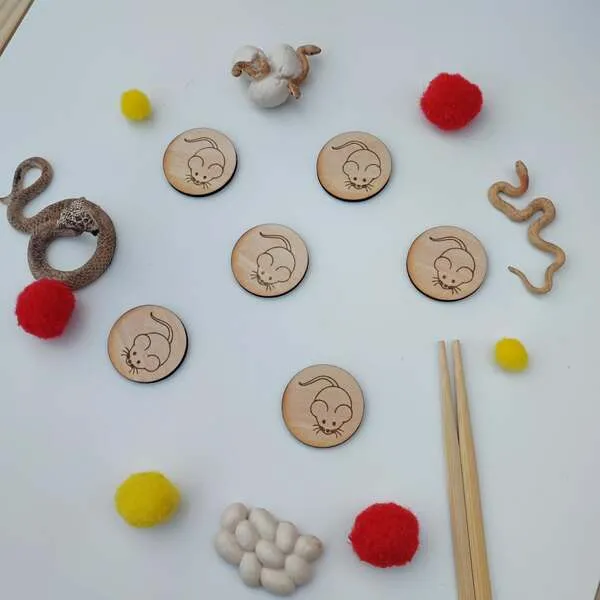 Jetons en bois gravés souris disposés avec pompons rouges et jaunes, éléments sensoriels et baguettes pour activité enfant thème Nouvel An chinois
