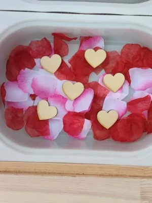 Plateau sensoriel avec pétales rouges et roses et cœurs en bois pour activité Saint-Valentin enfant