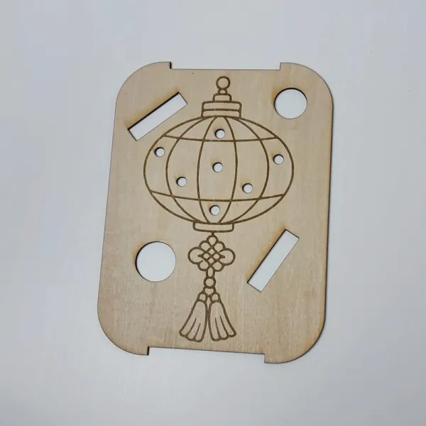 Plateau sensoriel en bois gravé représentant une lanterne chinoise avec trous de manipulation