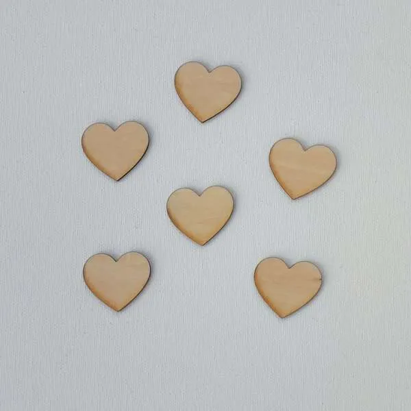 Petits cœurs en bois naturel disposés sur fond blanc pour activité sensorielle enfant
