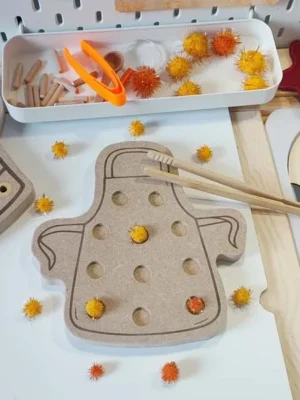 Plateau de motricité fine en bois en forme de tablier avec pompons à manipuler pour la Chandeleur