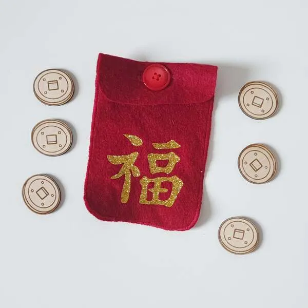Pochette rouge en feutrine avec symbole chinois de chance entourée de pièces en bois pour activité sensorielle du Nouvel An chinois