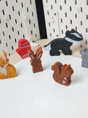 Figurines en bois du conte La moufle disposées debout sur fond clair