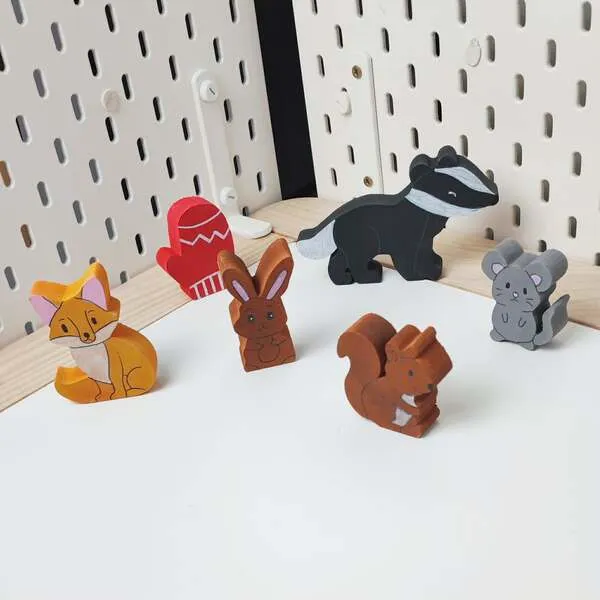 Figurines en bois du conte La moufle disposées debout sur fond clair