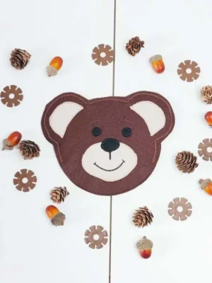 Tête d’ours en feutrine entourée de glands et de pommes de pin pour activité sensorielle enfant