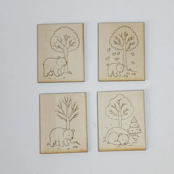 Cartes en bois gravées représentant un ours dans la forêt au fil des saisons