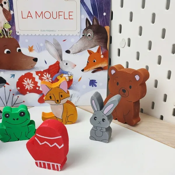 Figurines en bois du conte La moufle avec animaux et album jeunesse en arrière-plan
