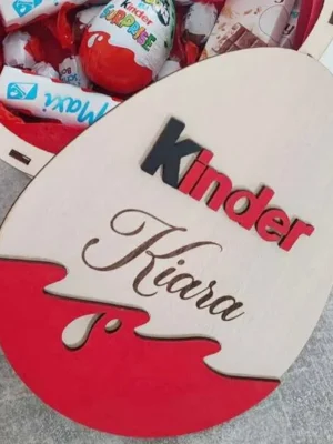 Boîte en bois en forme d’œuf personnalisée « Kiara », décor Kinder, ouverte et remplie de chocolats.