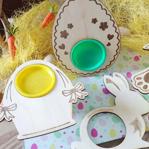 Supports en bois thème Pâques pour pots de pâte à modeler, formes œuf décoré, cloche et lapin, avec emplacements ronds colorés pour activité sensorielle.