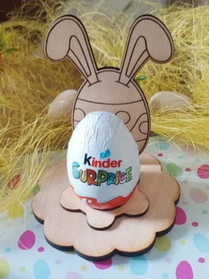 Support en bois pour œuf de Pâques avec silhouette de lapin aux grandes oreilles, posé sur socle fleur et tenant un œuf en chocolat.