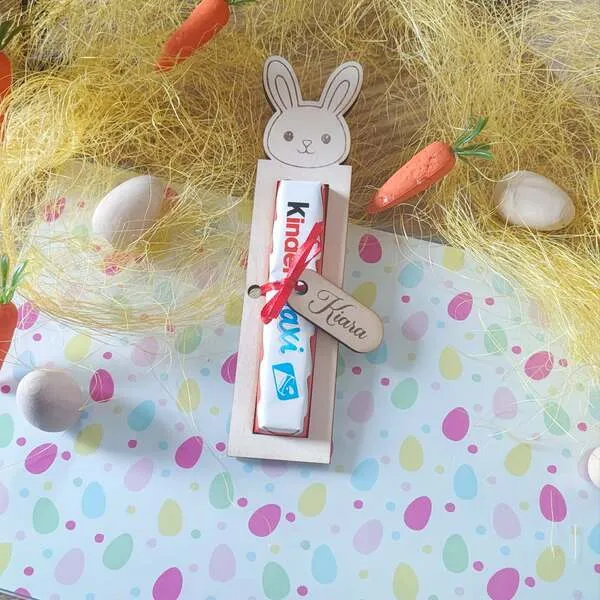 Support en bois lapin personnalisé contenant une barre de chocolat, présenté dans une décoration de Pâques