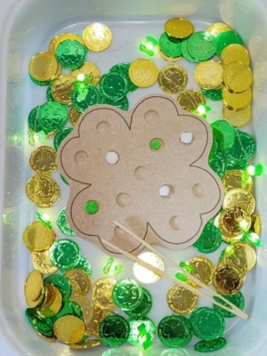 Activité sensorielle Saint Patrick avec insert trèfle en bois et pièces vertes et dorées.