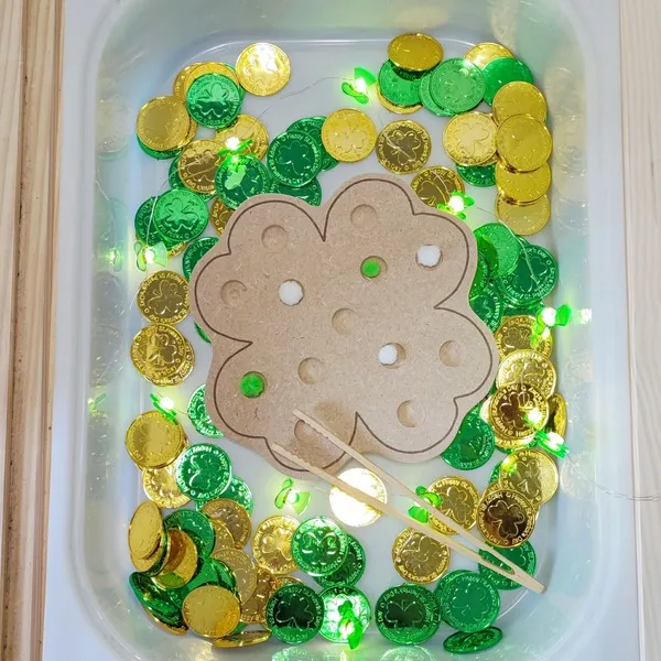 Activité sensorielle Saint Patrick avec insert trèfle en bois et pièces vertes et dorées.