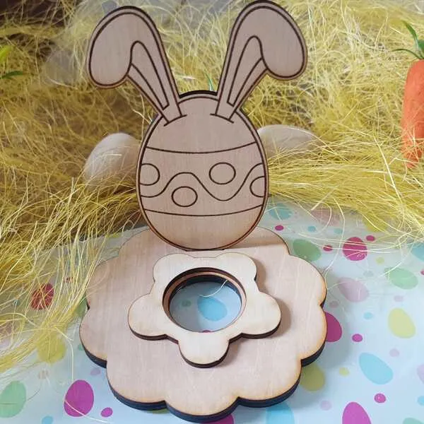 Support en bois pour œuf de Pâques avec silhouette d’œuf décoré et grandes oreilles de lapin, posé sur un socle en forme de fleur.