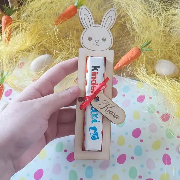 Support en bois lapin personnalisé tenu en main avec barre de chocolat et étiquette prénom gravée
