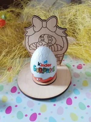 Support en bois pour œuf de Pâques avec panier gravé et grand nœud décoratif, posé sur un socle rond avec emplacement pour œuf en chocolat.