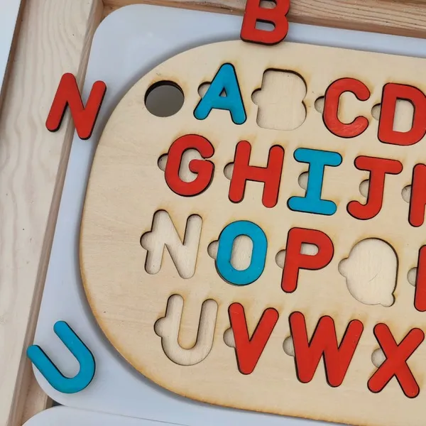 Gros plan sur un puzzle alphabet en bois avec lettres majuscules colorées à encastrer pour enfant