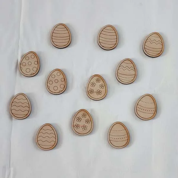 Jetons en bois en forme d’œufs décorés avec différents motifs pour activité éducative de Pâques.